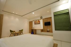 a bedroom with a bed and a table and a chair at Nova Yashraj Hotel in Rajkot