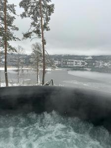 a bath tub with a view of a body of water at Modern Cabin With Panoramic Views in Hønefoss