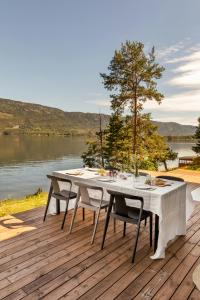 a table and chairs on a deck next to a lake at Modern Cabin With Panoramic Views in Hønefoss