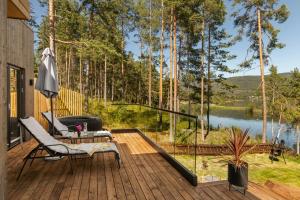 a deck with a chair and an umbrella and a lake at Modern Cabin With Panoramic Views in Hønefoss
