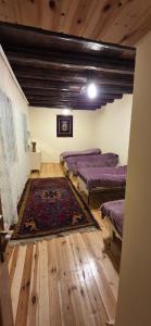 a room with three beds and a rug on a wooden floor at Khinalig Shaiq Guest House in Xınalıq