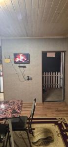 a living room with a table and a television on a wall at Khinalig Shaiq Guest House in Xınalıq