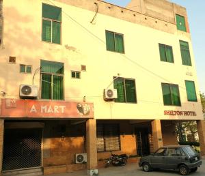 a building with a car parked in front of it at Shelton Hotel Johar Town Lahore in Lahore