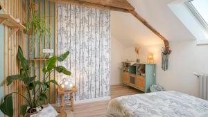 a bedroom with a bed and a plant in a room at Gîte Les Légendes du Plessis in Iffendic