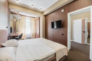 a bedroom with a large bed and a television on a wall at UIDE Apart hotel in Almaty