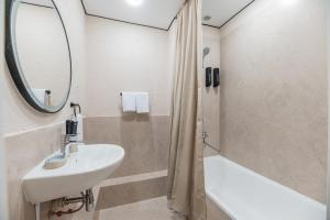 a bathroom with a sink and a mirror and a tub at UIDE Apart hotel in Almaty