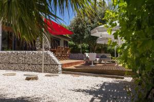 a backyard with a patio with chairs and an umbrella at Les Pieds dans Thau in Marseillan