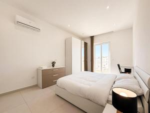 a white bedroom with a large bed and a desk at St Julians - Spinola Space by DNA in St. Julianʼs