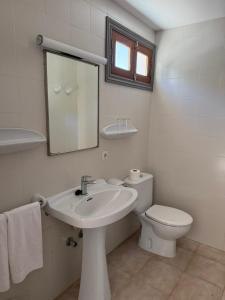 a bathroom with a sink and a toilet and a mirror at Hostal Playa in Cala Santanyi