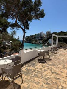 a patio with tables and chairs and a view of the water at Hostal Playa in Cala Santanyi