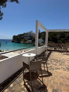 a table and chairs on a patio overlooking the beach at Hostal Playa in Cala Santanyi +29 photos