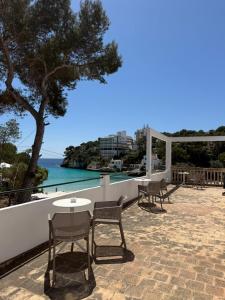 a patio with tables and chairs and a view of the water at Hostal Playa in Cala Santanyi