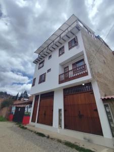 a white house with wooden doors and a balcony at Hotel La Terraza Raquireña in Ráquira