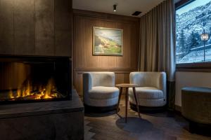 a room with two chairs and a fireplace at Hotel Auenhof in Lech am Arlberg