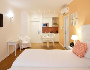 een slaapkamer met een wit bed en een keuken bij Rossio Apartments in Lissabon