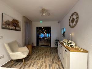 a living room with a chair and a dresser and a clock at Pensiunea La Cuscrii in Arad