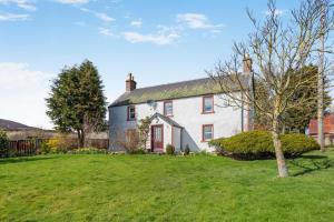 a white house with a tree in the yard at 3 Bed in Kirriemuir oc-96450 in Kirriemuir