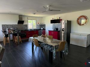 a kitchen with a table with chairs and a refrigerator at Villa oasis des laves in Sainte-Rose