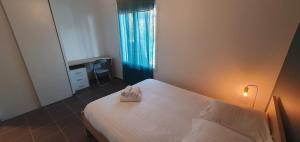 a bedroom with a white bed and a window at Maison familiale Montardon in Montardon