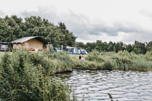 a young girl walking along a river with a tent at Vakantiepark de Kleine Wielen in Leeuwarden