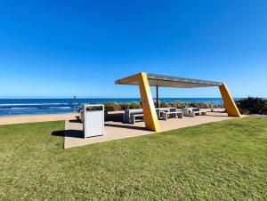 a picnic shelter on the beach with the ocean in the background at Good price Apartment self check-in in Geraldton