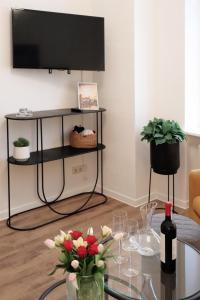 ein Wohnzimmer mit einem Tisch mit Blumen und einem Fernseher in der Unterkunft Altmarktstudio1 in Cottbus