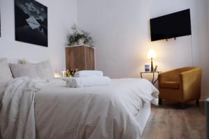 ein Schlafzimmer mit einem weißen Bett und einem Stuhl in der Unterkunft Altmarktstudio1 in Cottbus