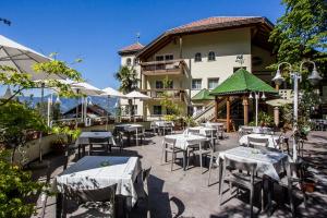 a restaurant with tables and chairs in front of a building at Hotel Tenz in Montagna