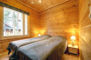 a bedroom with a bed in a wooden cabin at Puttitie 4B in Tahkovuori +2 photos