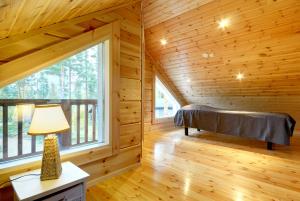 a bedroom in a log cabin with a bed and a window at Puttitie 4B in Tahkovuori