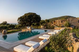 a pool with lounge chairs next to a resort at Les Paillers de Bodri - Vue mer et piscine - Adults Only in Corbara