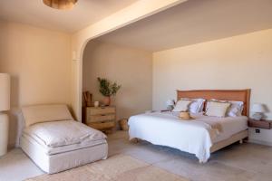a bedroom with a bed and a ottoman at Les Paillers de Bodri - Vue mer et piscine - Adults Only in Corbara