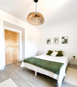 a white bedroom with a bed and a chandelier at Refúgio do Bugalho - Casa da Oliveira in Alandroal