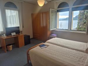 a bedroom with two beds and a tv and two windows at Hotel Terminus in Garda