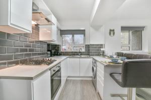 uma cozinha com armários brancos e um forno com placa de fogão em Sachin's 2 Bedrooms Apartment em Londres