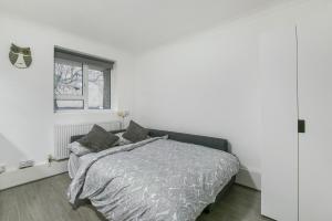 a white bedroom with a bed and a window at Sachin's 2 Bedrooms Apartment in London