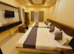 two beds in a hotel room with a television at shree krishna Hotel in Ujjain