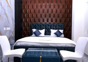 a bedroom with a blue bed with two white chairs at Hotel skyline in Visakhapatnam