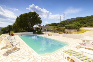 a swimming pool with chairs and a house at Panoramic Seaview Coastal Retreat with Pool in Cugnana