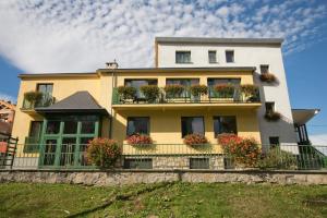 a yellow house with potted plants on a balcony at Willa Ewa in Lądek-Zdrój