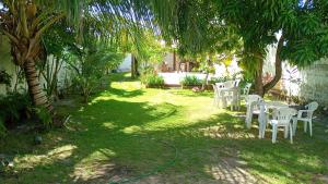 ein Garten mit weißen Tischen und Stühlen unter Bäumen in der Unterkunft Arborizado in Camaçari
