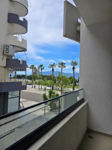 a balcony with a view of the beach and palm trees at Suites By Jordan's Hotel in Vlorë