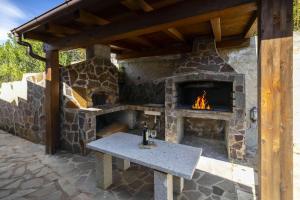 a stone fireplace with a table in front of it at Panoramic Seaview Coastal Retreat with Pool in Cugnana