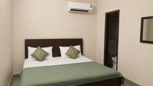 ein Schlafzimmer mit einem Bett mit grünen Laken und Kissen in der Unterkunft Hotel The Height in Chandīgarh