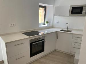 a white kitchen with a stove and a sink at Apartamento centro Cubelles in Cubelles