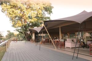 a deck with tables and chairs under umbrellas at Chamabondo Luxury Tented Camp in Victoria Falls