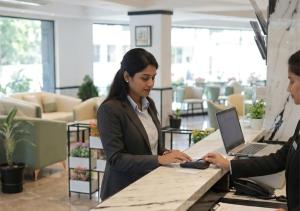 two women standing at a table with a laptop at Downtown Business Hotel in Singapperumālkovil