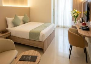 a hotel room with a bed and a desk at Downtown Business Hotel in Singapperumālkovil