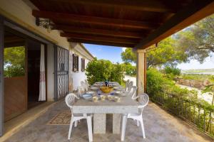 a table with white chairs on a patio at Panoramic Seaview Coastal Retreat with Pool in Cugnana