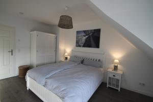 a bedroom with a white bed with two night stands and two lamps at Ferienhaus Oberhüs - Das Familien-Ferienhaus an der Ostsee in Scharbeutz